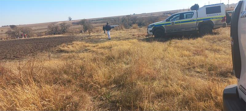 A man is standing next to a truck in a field.