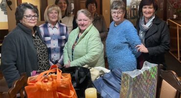 A group of women standing around a table with bags.