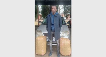 A man standing next to a car with bags.