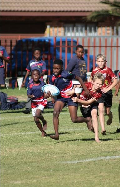 A group of children playing rugby on a field.
