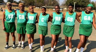 A group of women in green uniforms standing on a court.