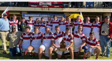 The rugby team is posing for a photo with their trophy.