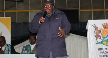 A man in a blue jacket speaking into a microphone.