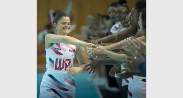 A woman in a cheer uniform shaking hands with other women.