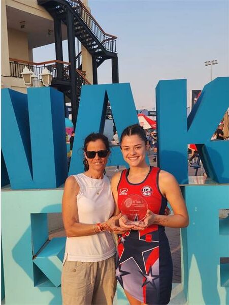 Two women standing next to each other holding an award.