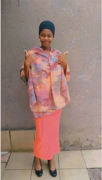 A woman in a pink dress and head scarf.
