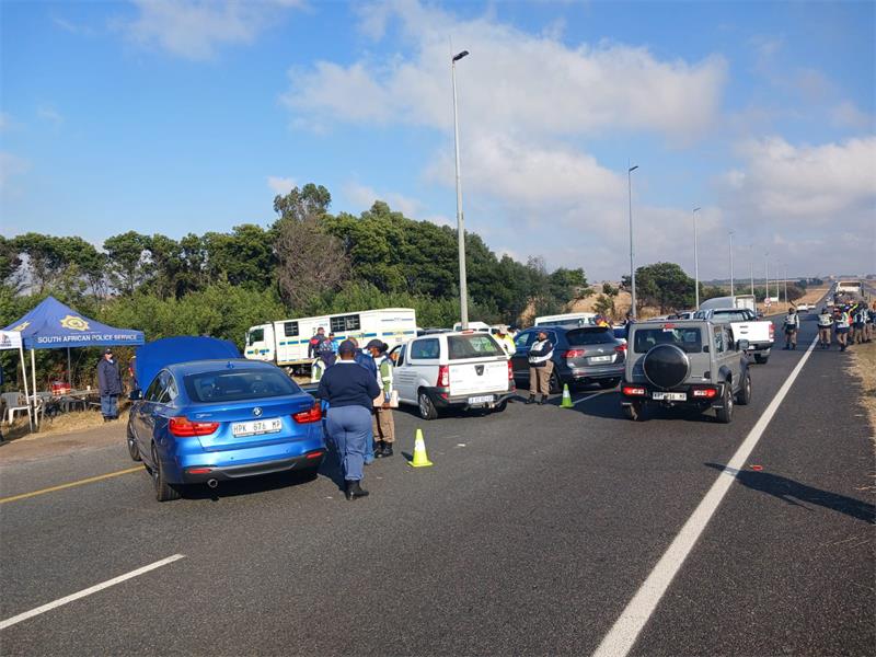 A police officer is standing next to a car that is parked on the side of the road.