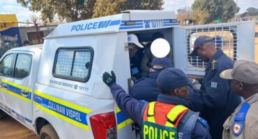 Police officers are loading a vehicle with people.