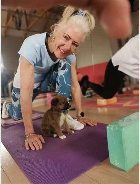 A woman laying on a yoga mat with three puppies.