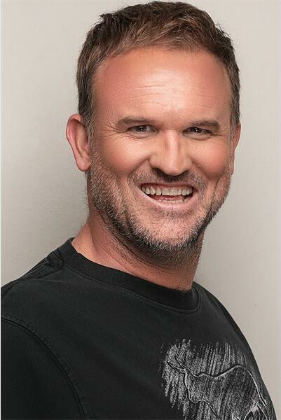 A man with a black t - shirt smiling.
