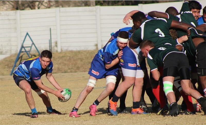 A group of young men playing rugby on a field.