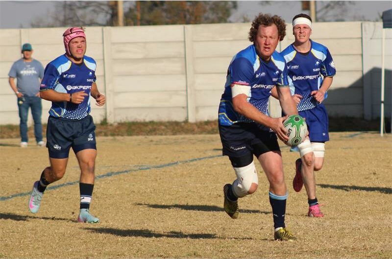 Rugby players in blue and white uniforms running on the field.
