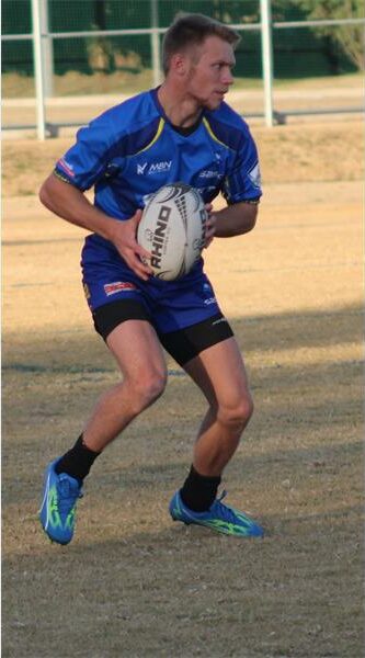 A man in blue and black is holding a rugby ball.