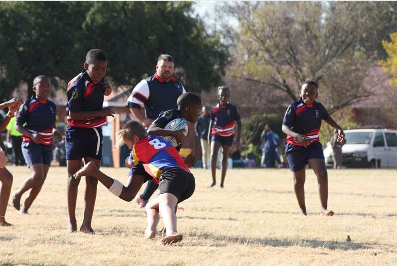 A group of young boys playing rugby on a field.