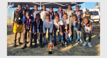 A group of young people posing for a photo with their trophies.