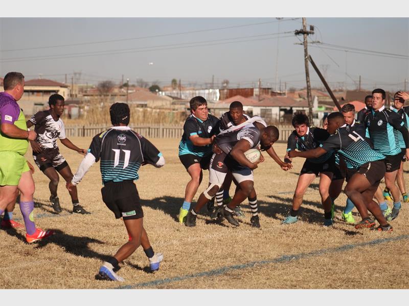 A group of men playing rugby on a field.