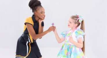 A young girl is holding an ice cream to a young girl.