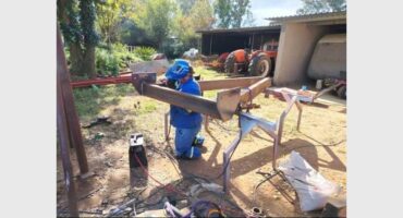 A man is working on a wooden frame in the yard.