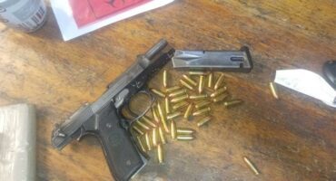 A gun and a box of bullets on a table.