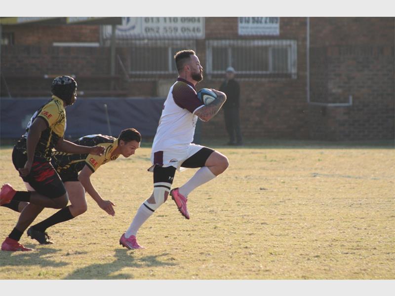 A man running with a rugby ball in his hand.