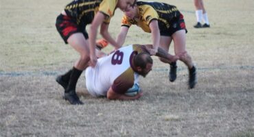 Two men are playing rugby on the field.