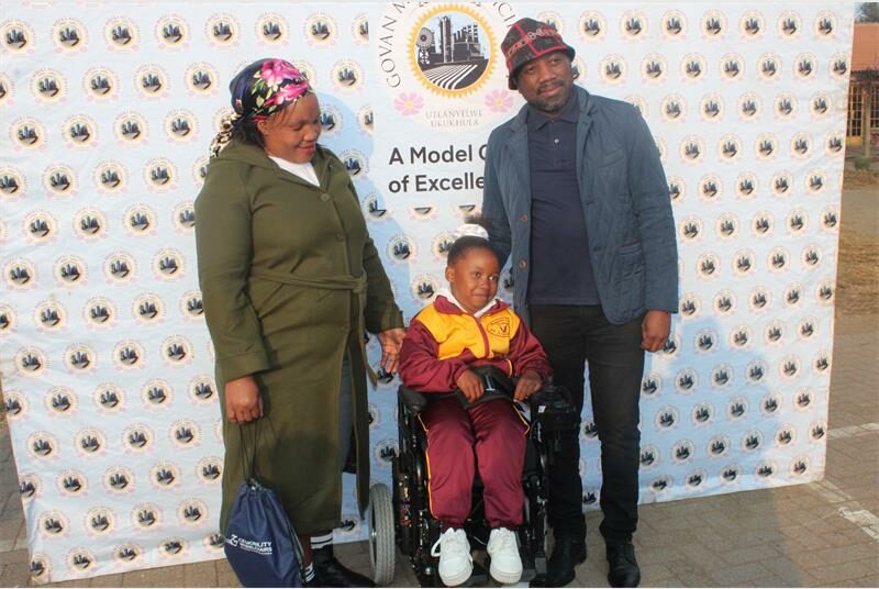 A man and woman standing next to a child in a wheelchair.