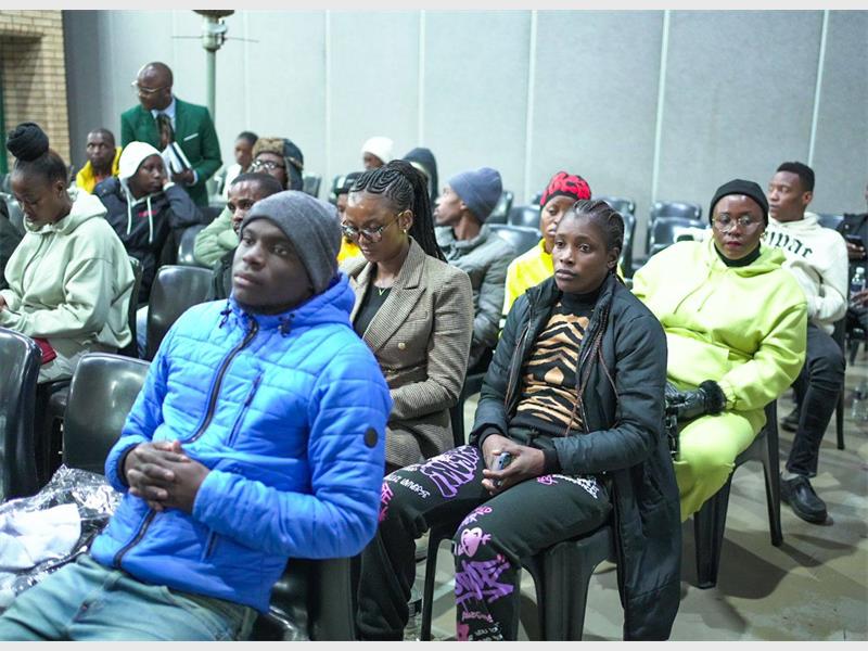 A group of people sitting in chairs and one is holding a cell phone.