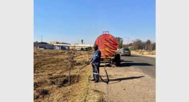 A man is standing next to a truck on the side of the road.