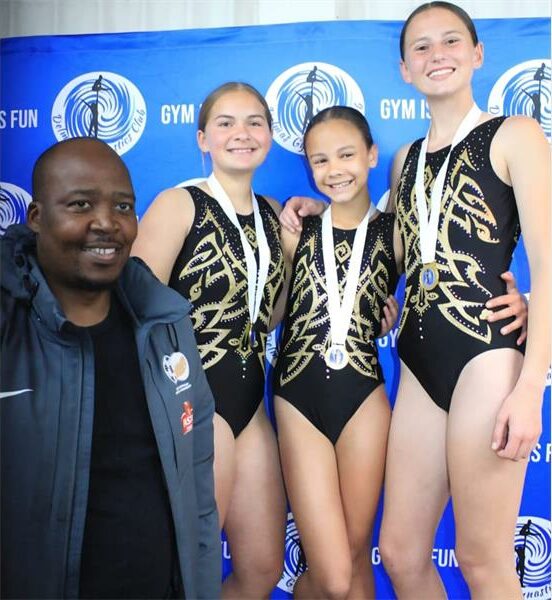Three girls in swimsuits pose for a photo with a man.