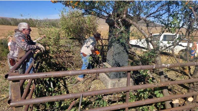Two men are working on a fence in the field.