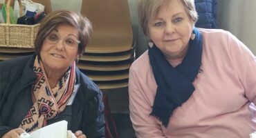Two women sitting at a table with books.