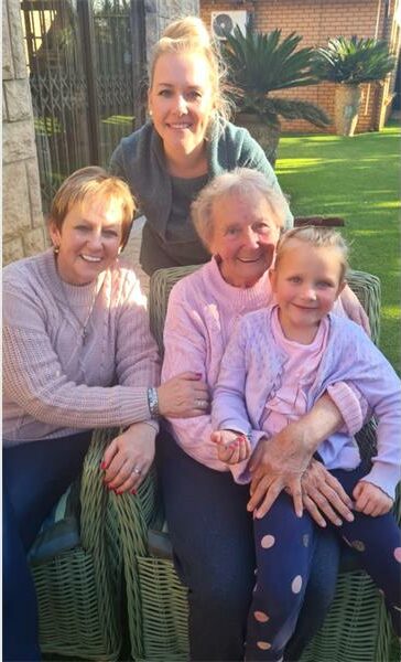 Three women and a little girl sitting on a wicker chair.
