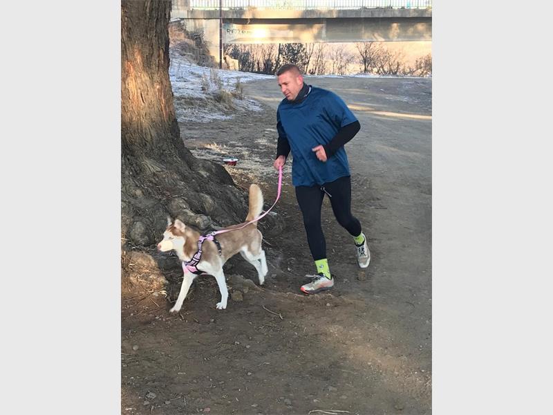 A man running with his dog on a leash.