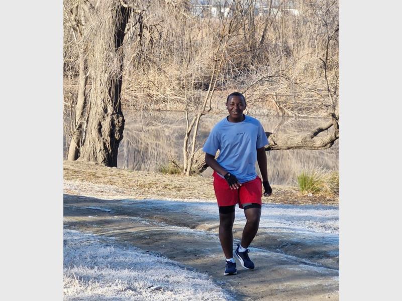 A man in red shorts and a blue shirt is walking on a path.