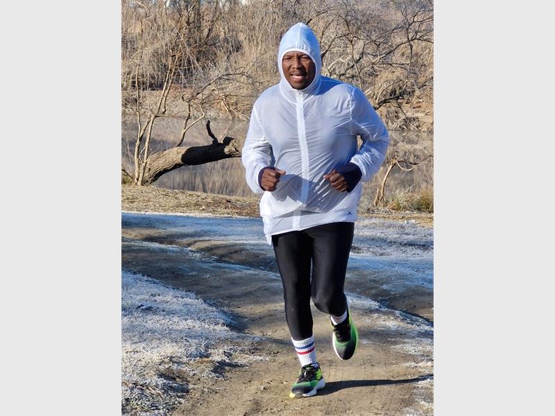 A man in a white jacket and black pants running.