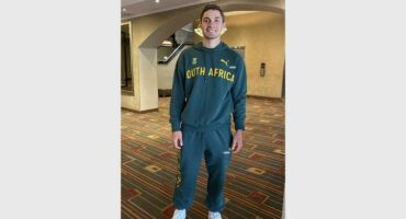 A man in a green and yellow sweatsuit standing in a hallway.