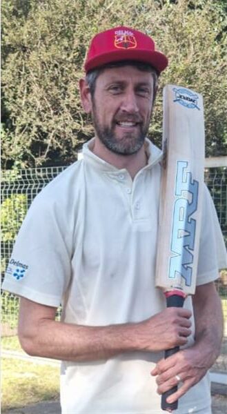 A man in a red cap holding a cricket bat.
