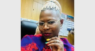 A woman with glasses and a colorful shirt.