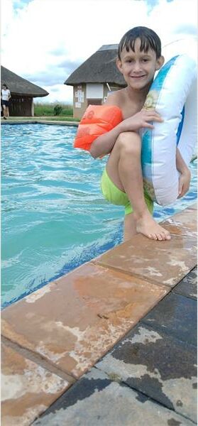A young boy is sitting on the edge of a pool.