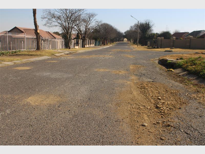 A street with a dirt road and a fence.
