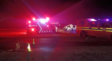 A car is parked next to an ambulance at night.