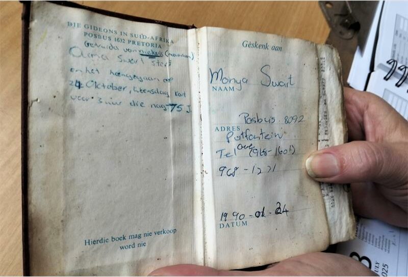 A person holding an open book with writing on it.
