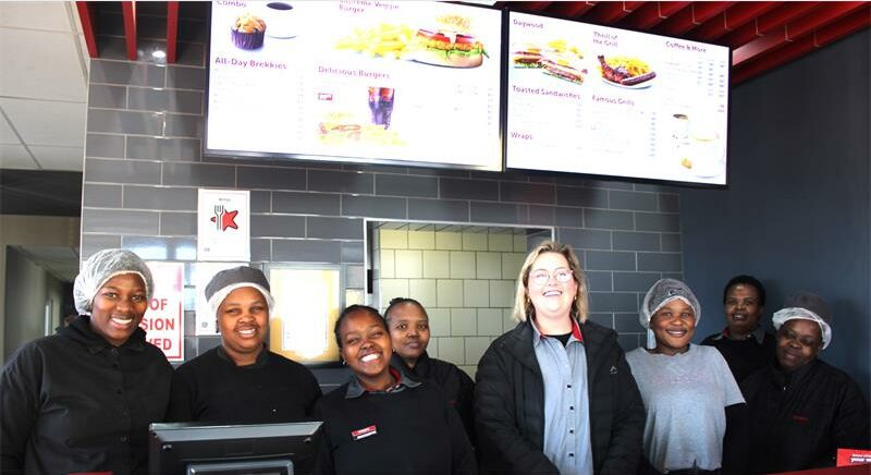 A group of people standing in front of a fast food restaurant.