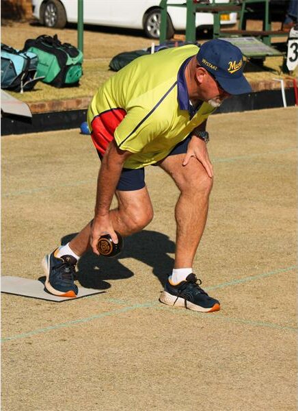 A man bending over to pick up a ball.