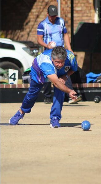 A man in blue and white playing a game of bowling.