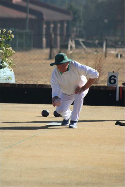 A man in white playing a game of bowls.