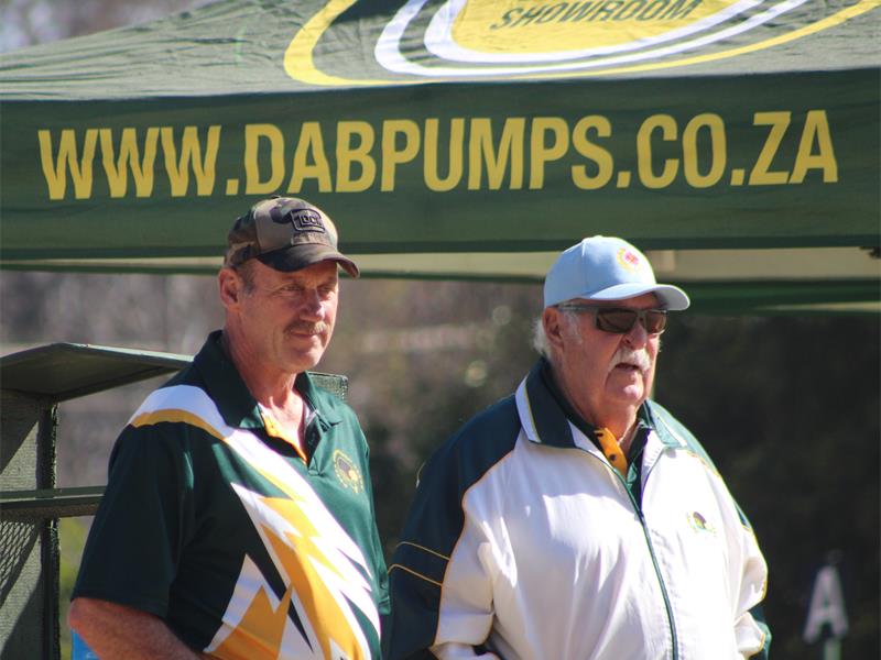 Two men in yellow shirts posing for a photo.