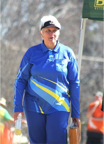A woman in blue and yellow clothing walking on a road.