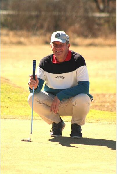 A man kneeling down on a golf course with a putt.