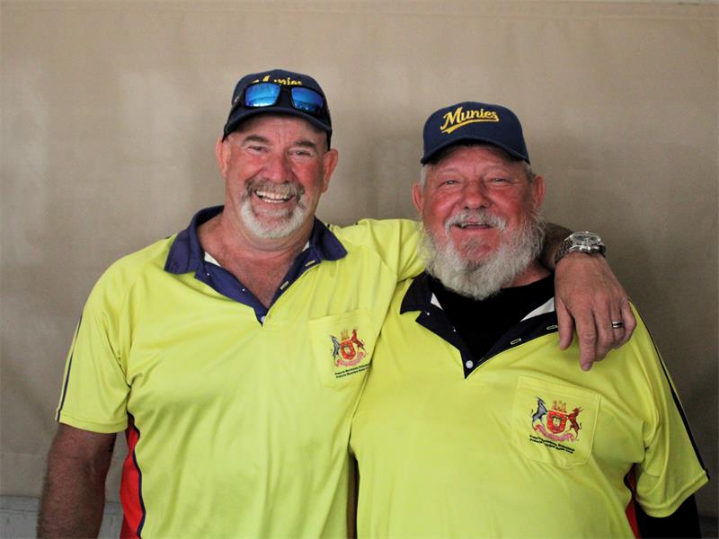 Two men in yellow shirts posing for a photo.